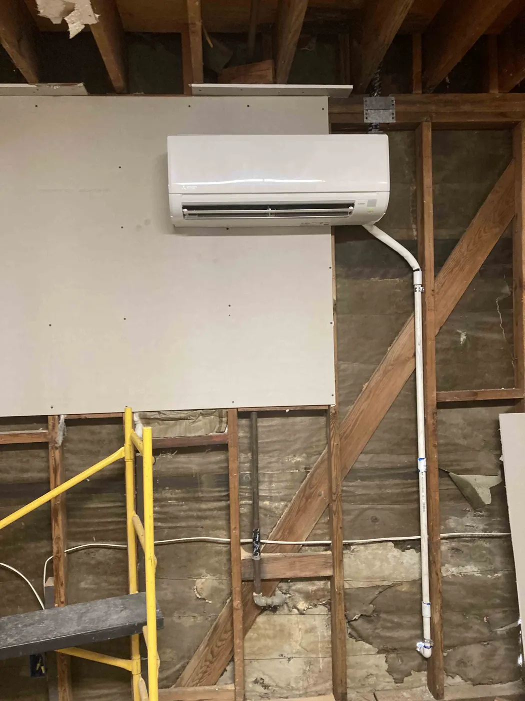 Ductless mini split indoor unit installed on a wall with framing exposed